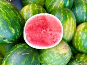 Half watermelon on top of a bunch of whole watermelons