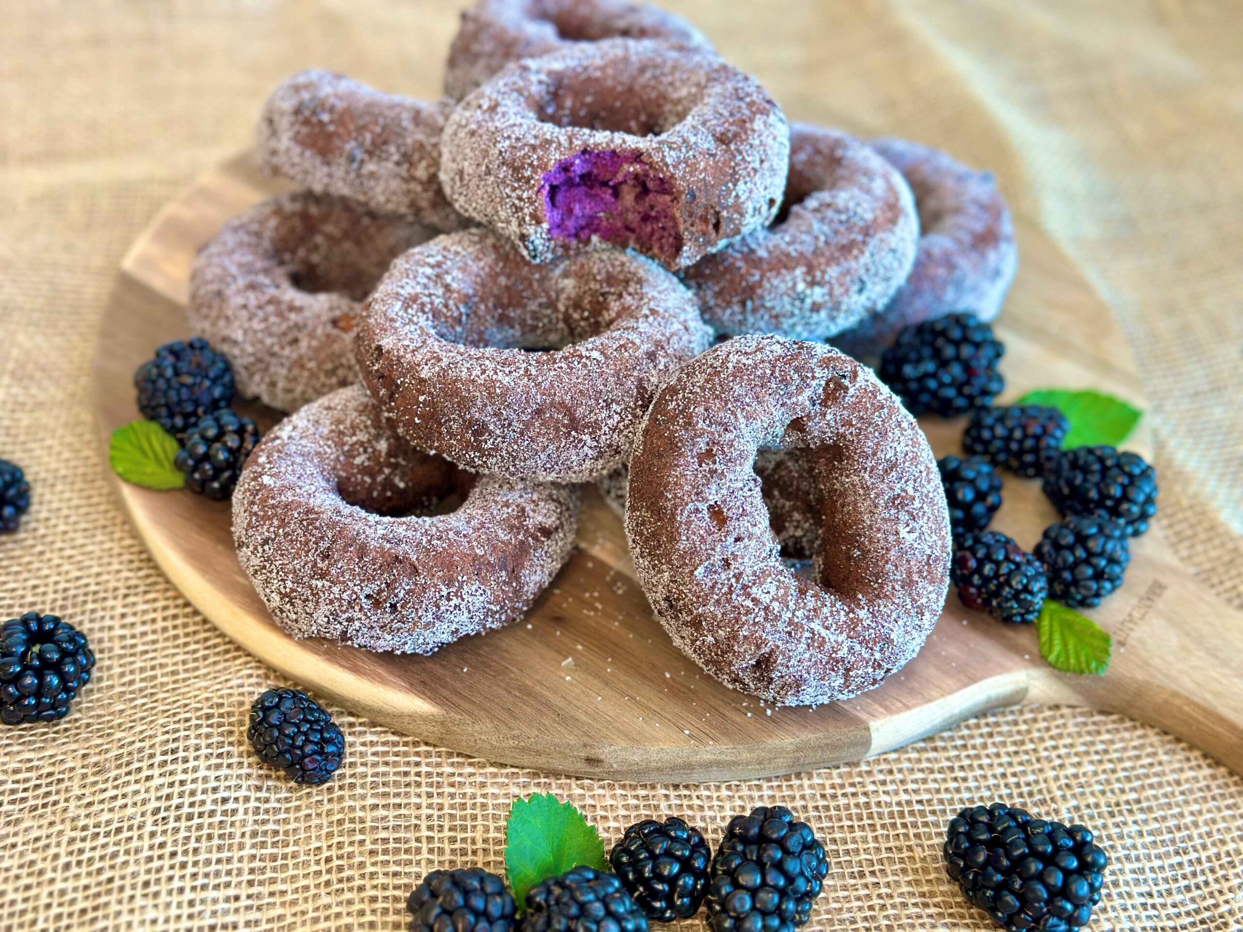 Stack of blackberry donuts with fresh blackberries around it