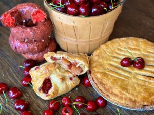 Assorted cherry pastries near a bucket of cherries