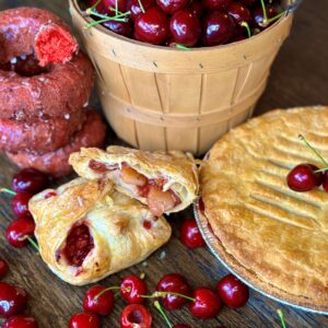 Assorted cherry pastries near a bucket of cherries